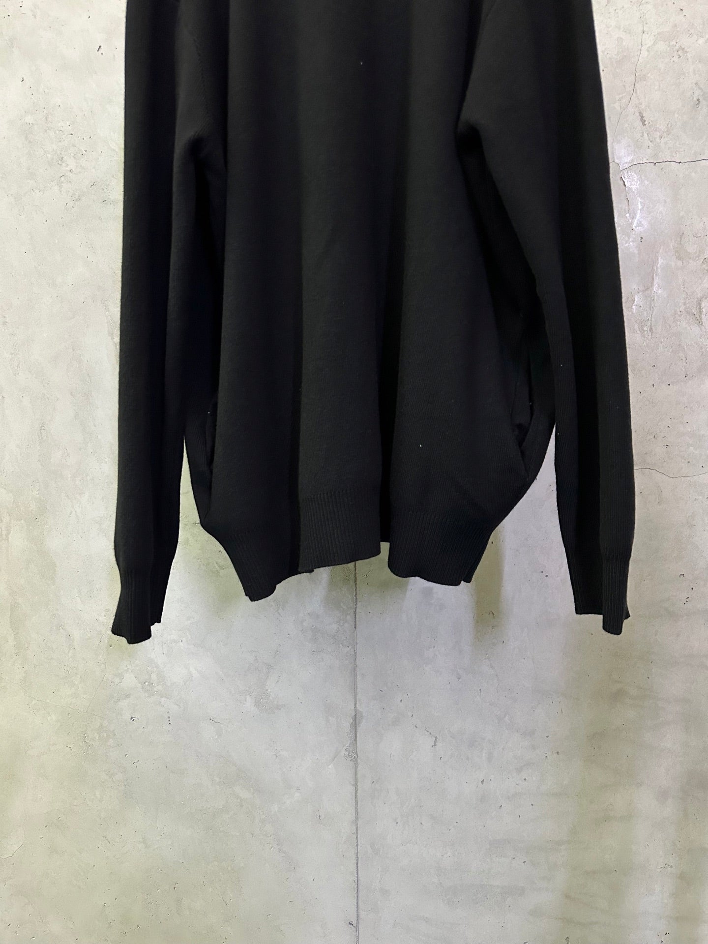 Black long coat back close-up with long sleeves and curved hemline