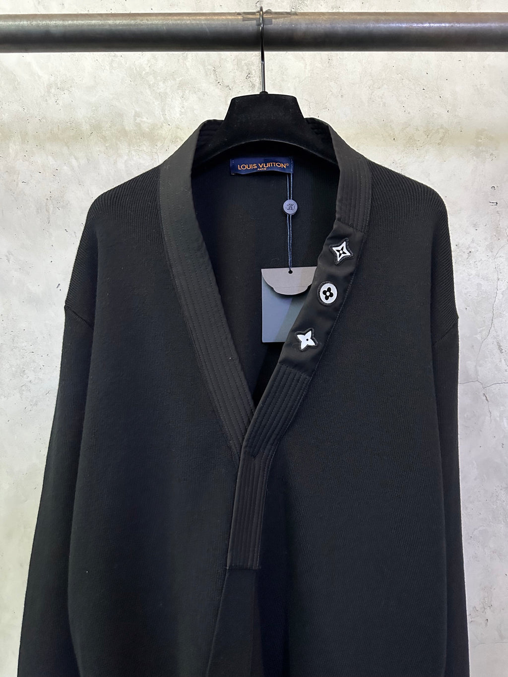 Black long coat front close-up with shawl lapel and decorative lapel icon trim