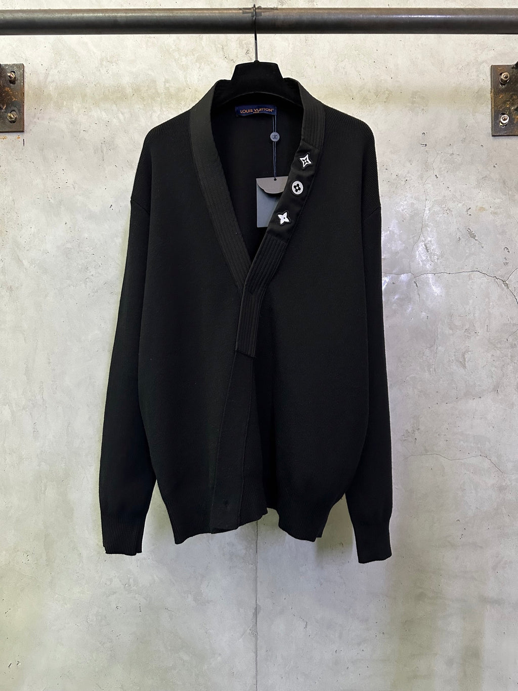 Black long coat with shawl lapels and decorative lapel icons on a hanging hanger