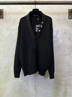 Black long coat with shawl lapels and decorative lapel icons on a hanging hanger