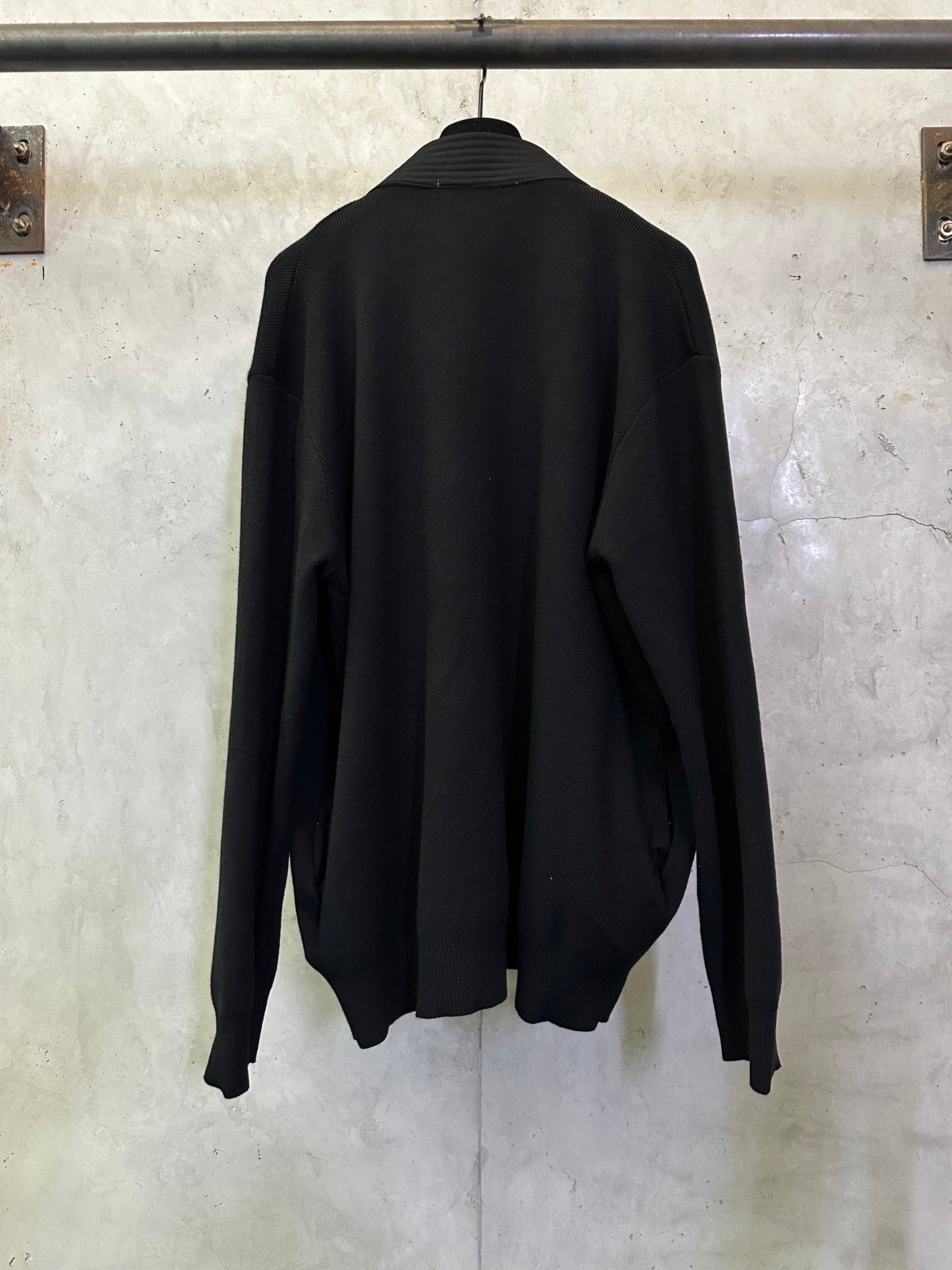 Black long coat back view with long sleeves and full length hem on a hanger