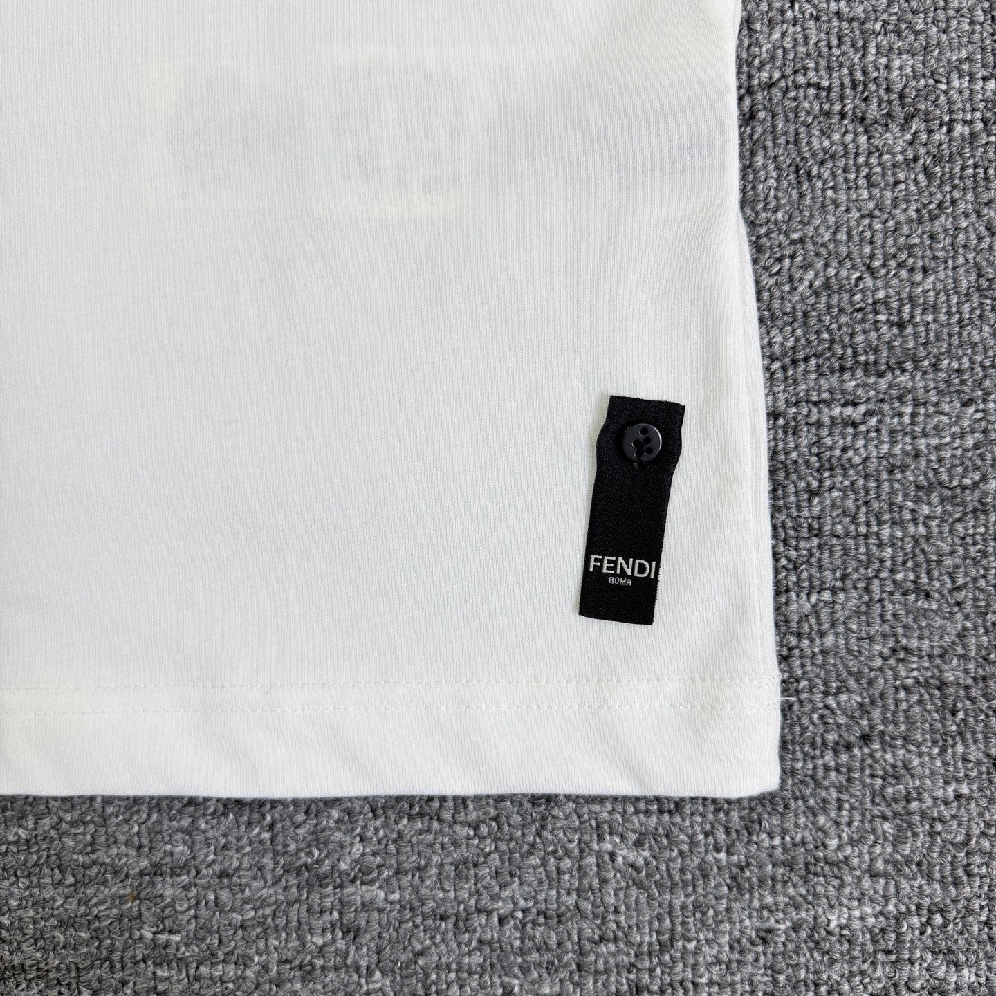 White Fendi T-shirt side hem with small black Fendi label tab.