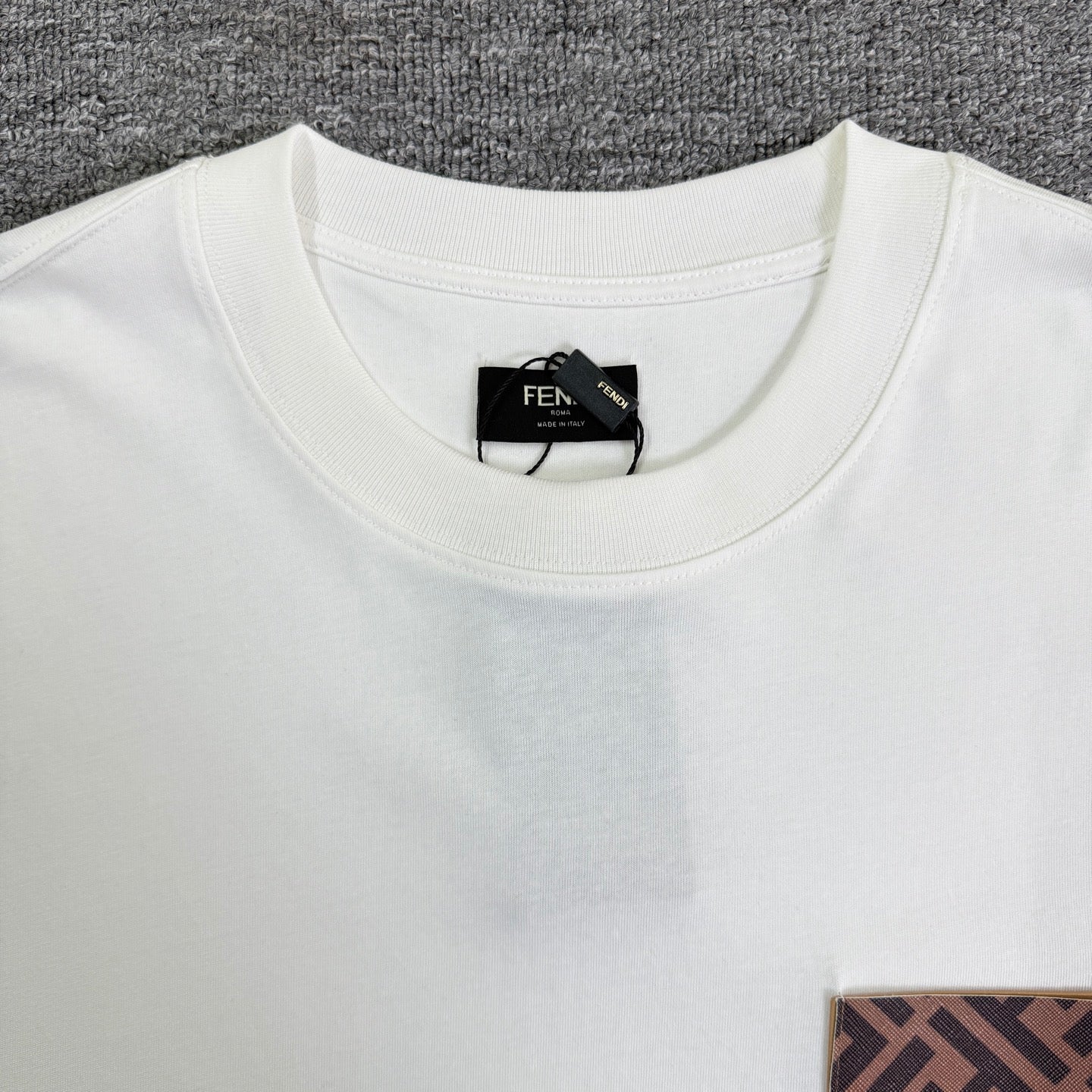 White Fendi T-shirt closeup: ribbed crew neck and black neck label.