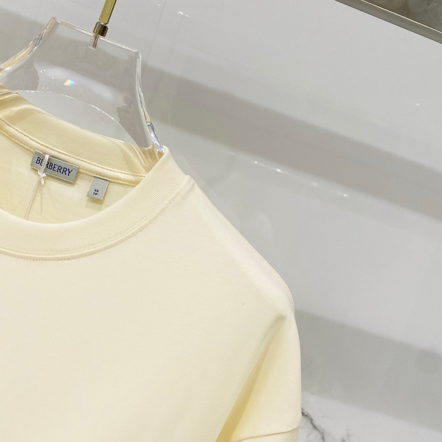 Pale yellow short-sleeve T-shirt showing shoulder seam and smooth fabric finish
