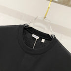 Black crew-neck T-shirt close-up with neckline stitching and small brand tag.