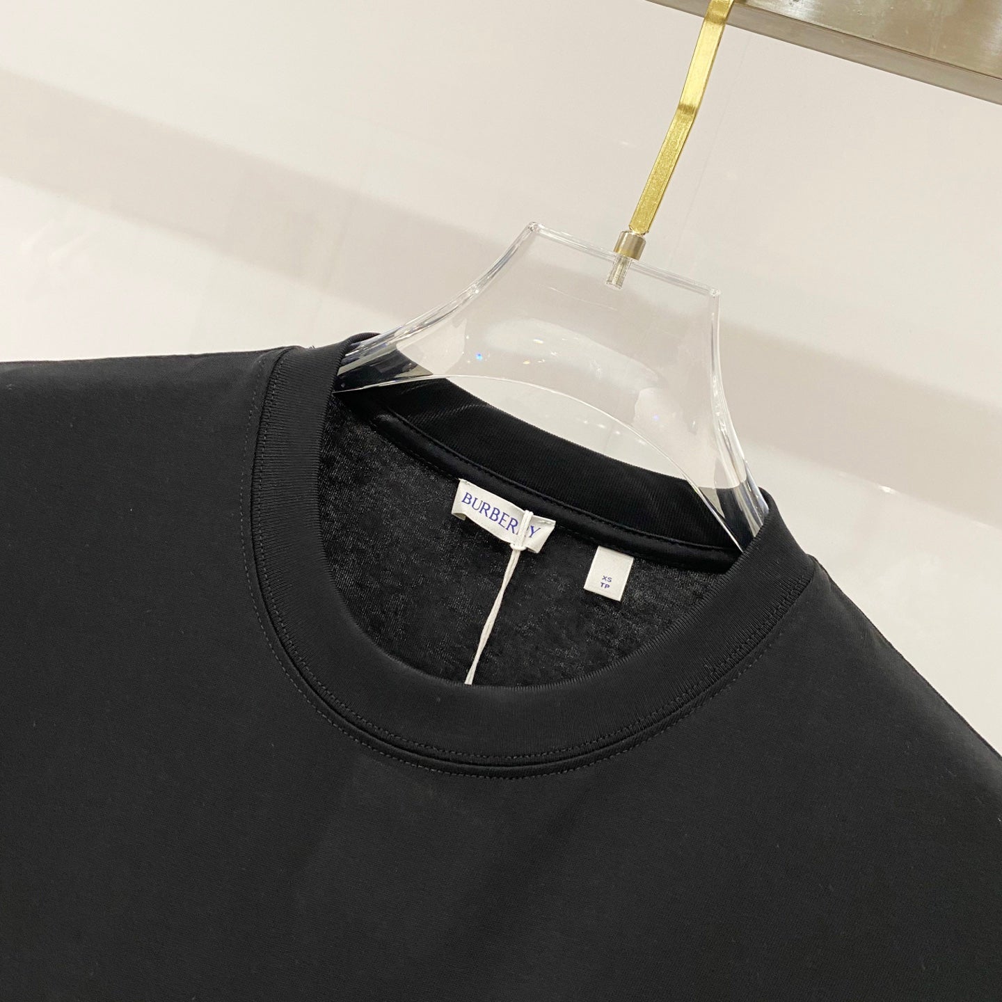 Black crew-neck T-shirt close-up with neckline stitching and small brand tag.