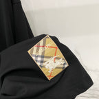 Black T-shirt with multicolor Burberry-style check patch appliqué on the chest.
