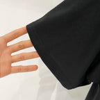 Black T-shirt sleeve hem with visible stitching, held by a hand for scale.