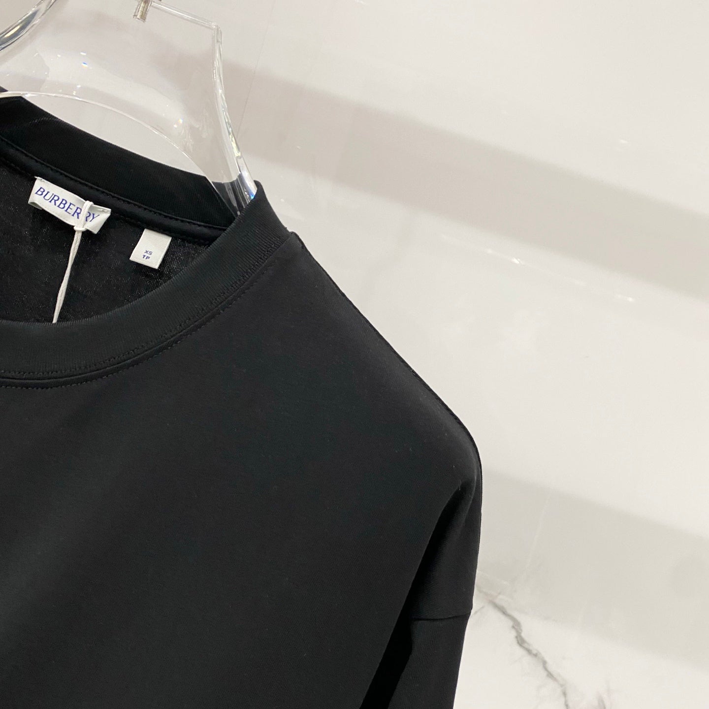 Black short-sleeve T-shirt close-up of shoulder seam and neckline edge.