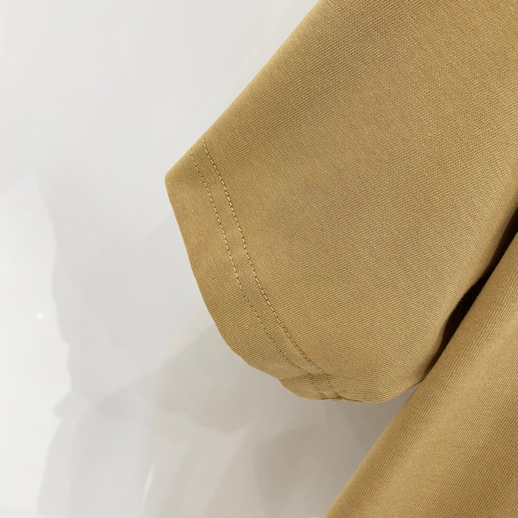 Tan short-sleeve T-shirt sleeve cuff with visible hem stitching