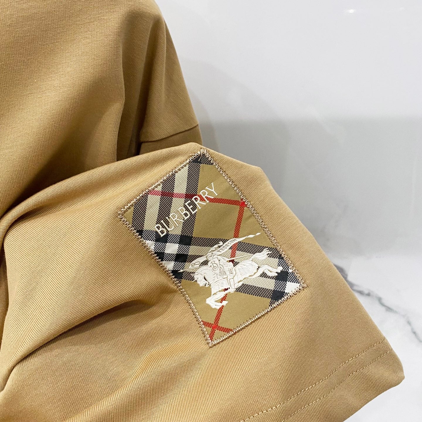 Tan short-sleeve T-shirt with embroidered horse-and-checkered back graphic