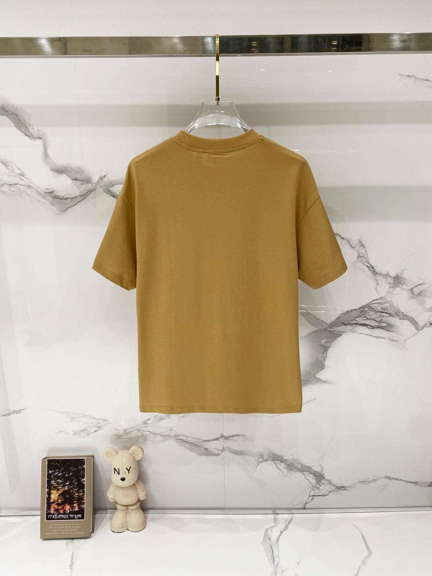 Tan crew-neck short-sleeve T-shirt on hanger, back view