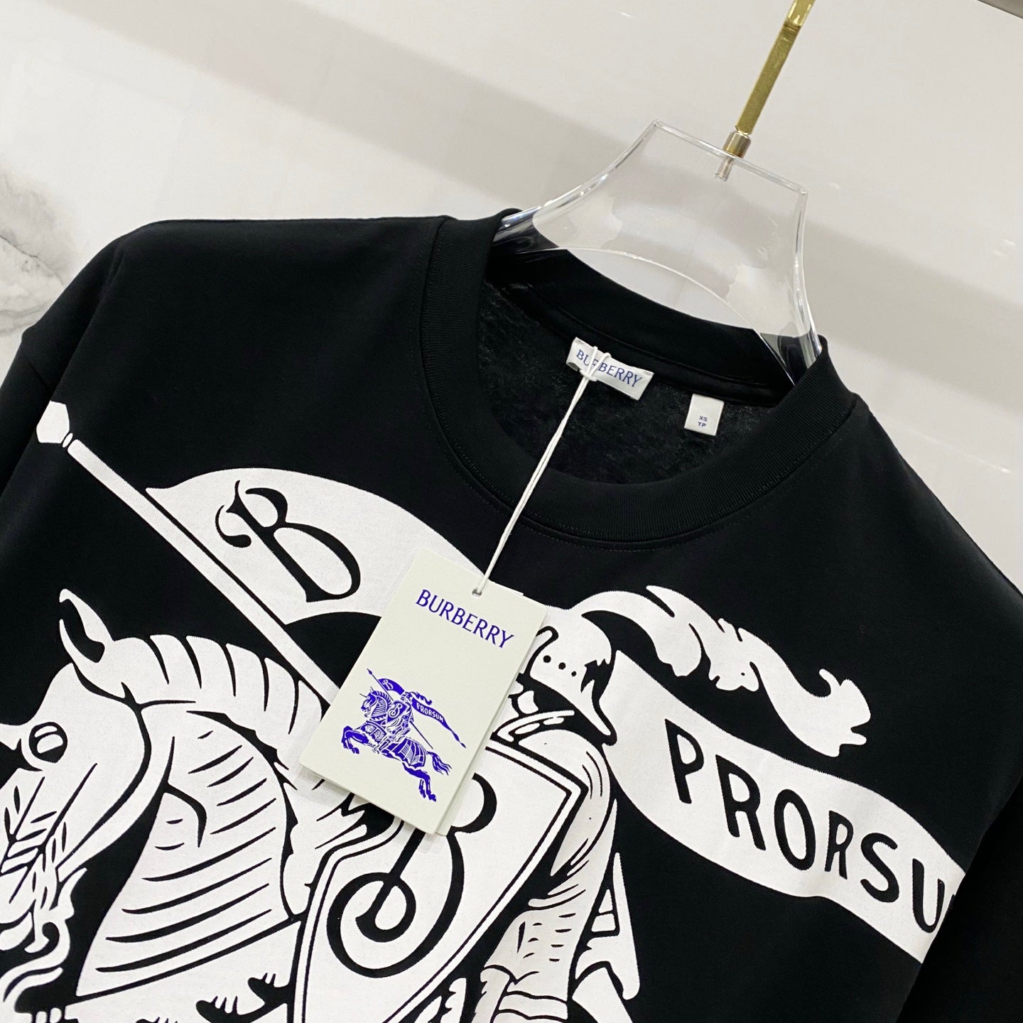 Black T-shirt with white horse-and-rider graphic and blue logo detail