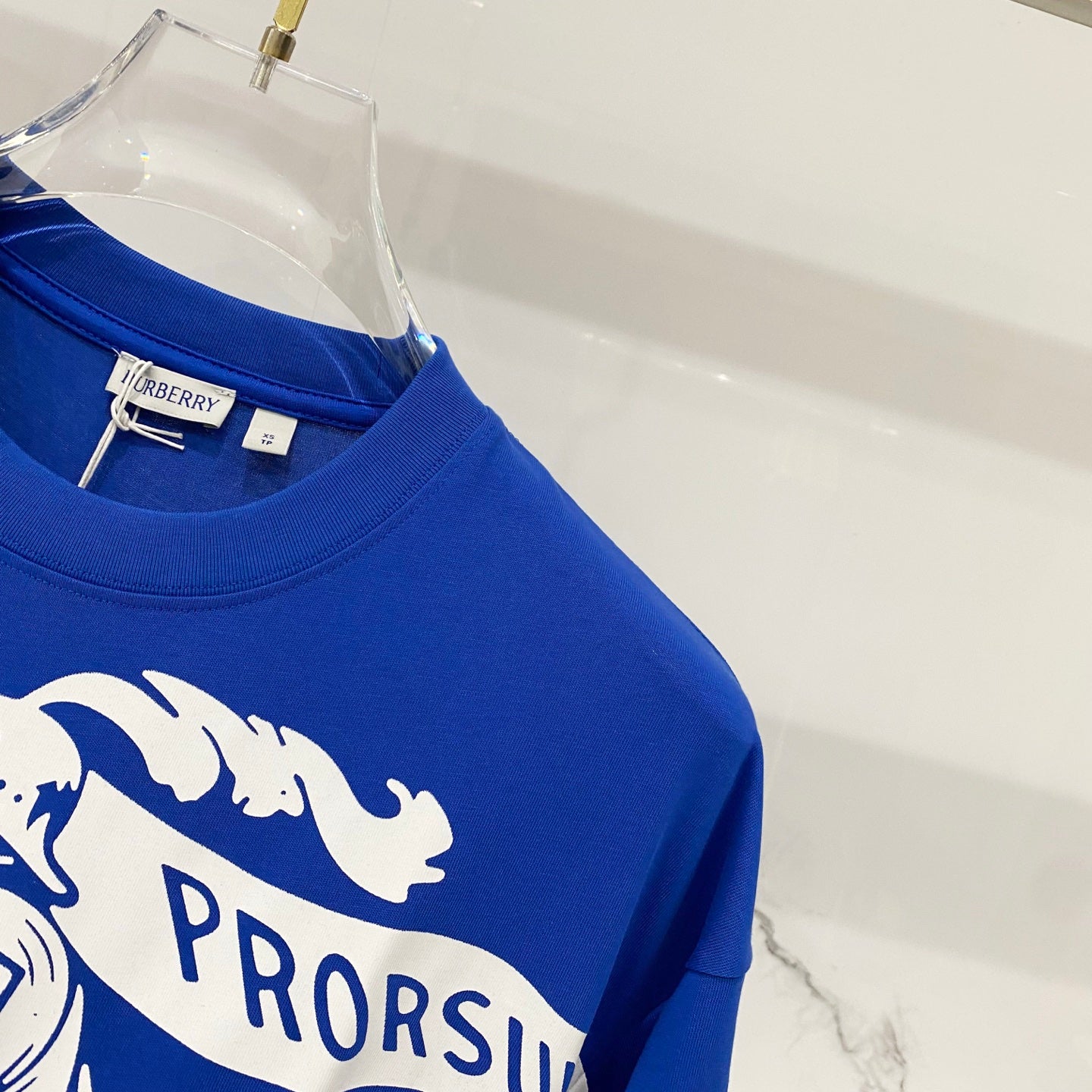 Blue T-shirt sleeve and shoulder with partial PRORSUM graphic print