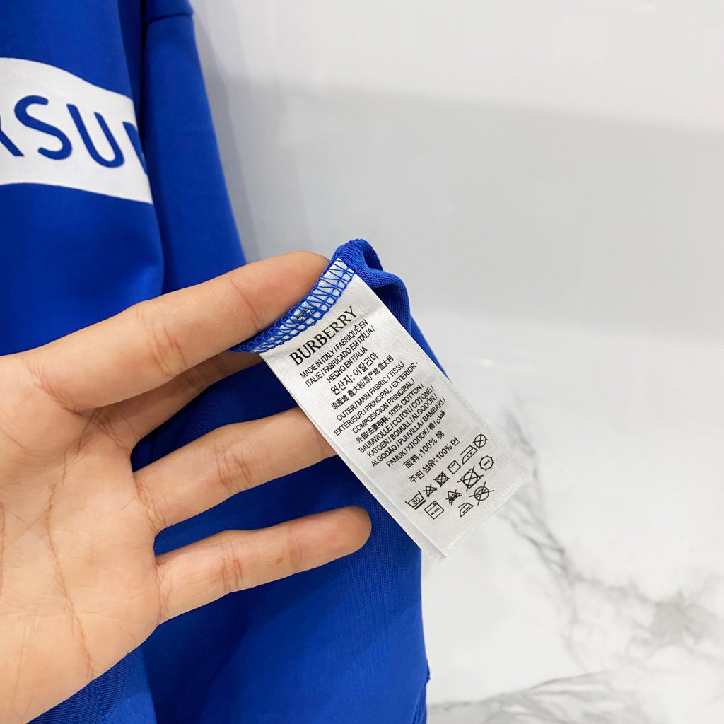 Blue T-shirt care label tag at side neck with printed size and symbols