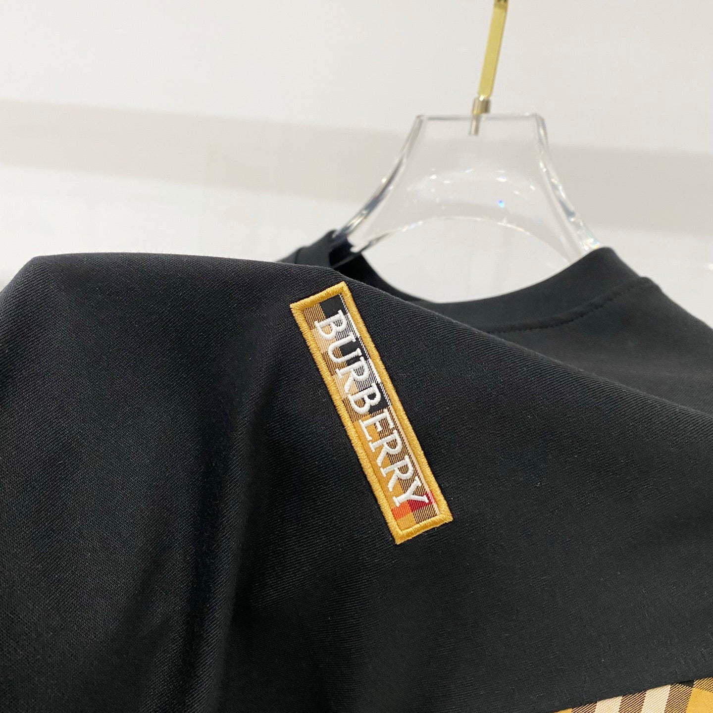 Close-up of black T-shirt sleeve with Burberry logo patch