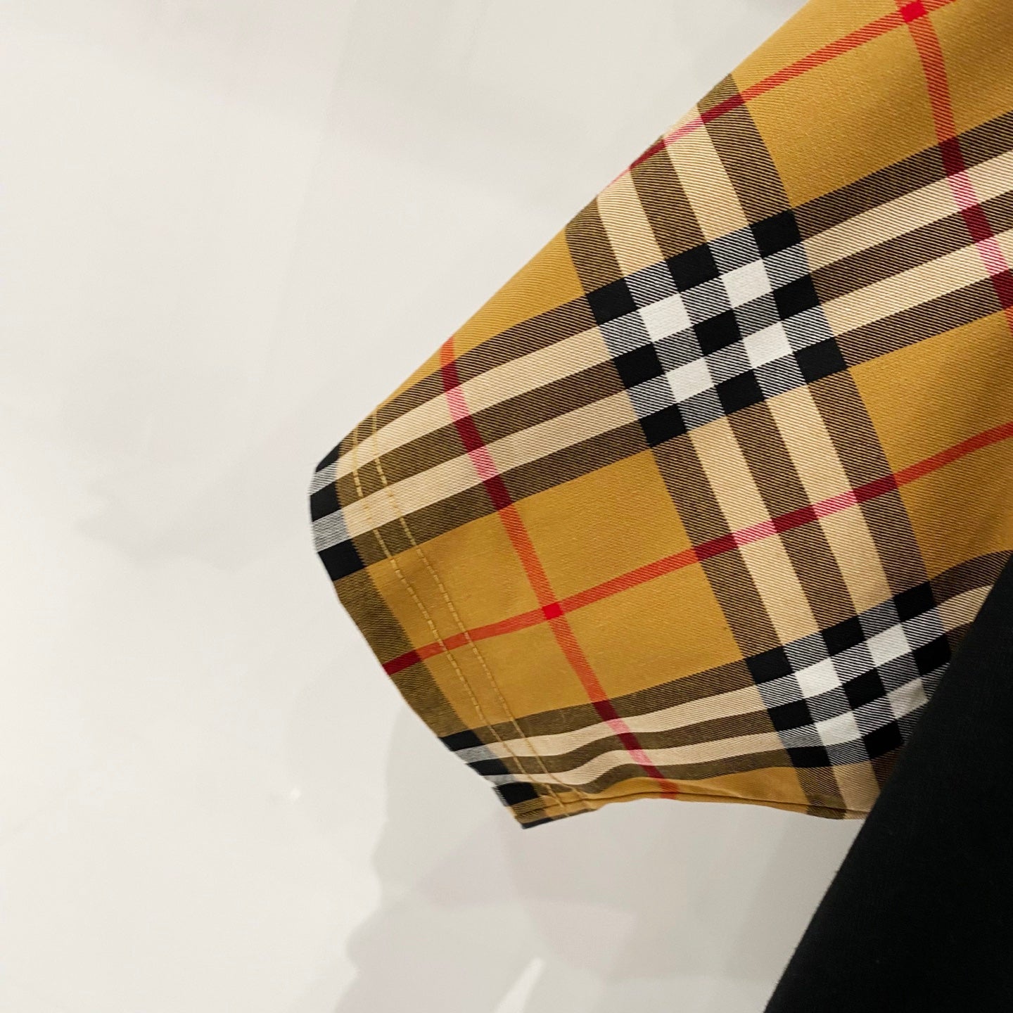 Close-up of check-pattern sleeve cuff in tan, red, black, and white
