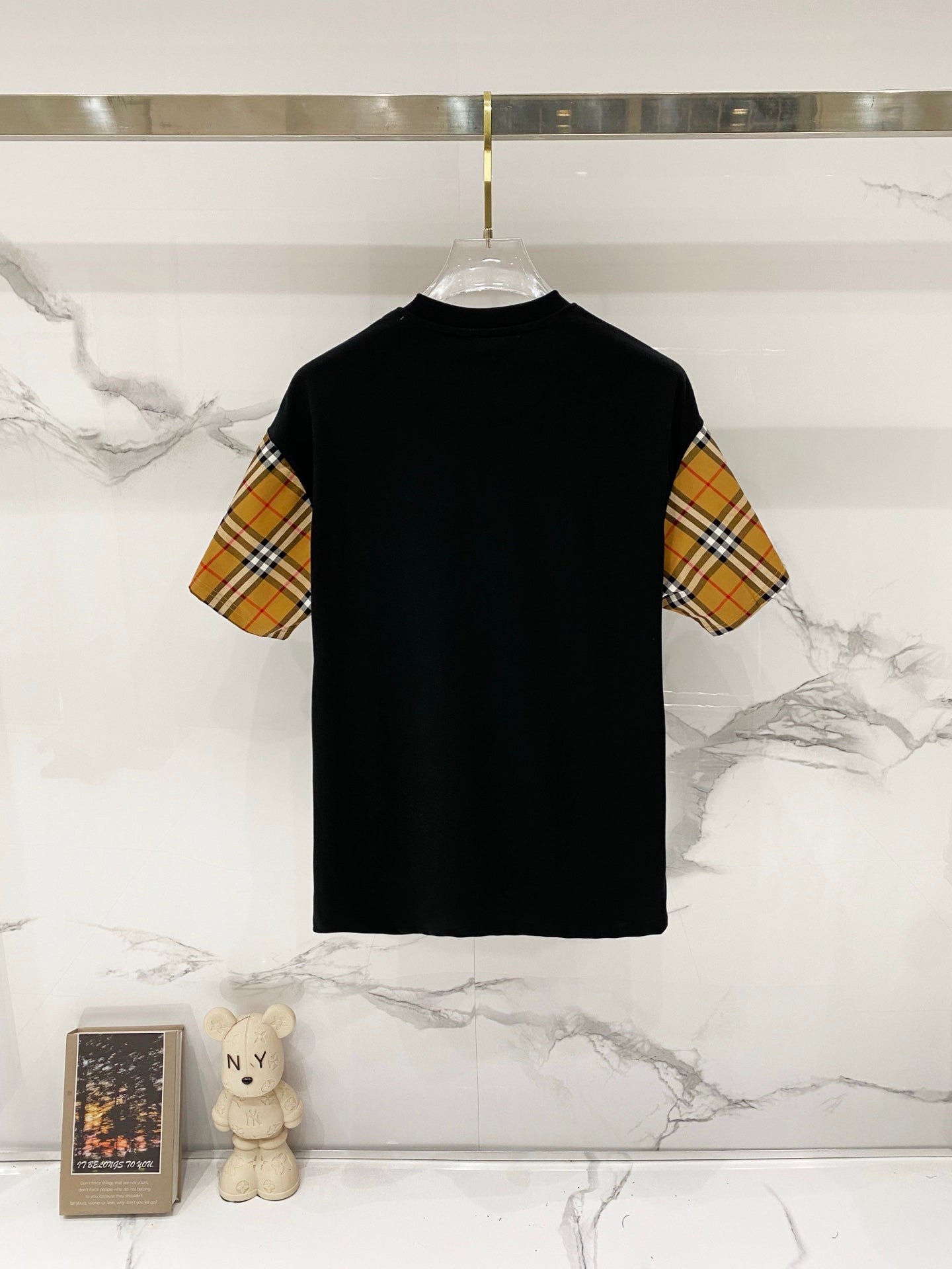 Black short-sleeve T-shirt on hanger with check-pattern sleeves