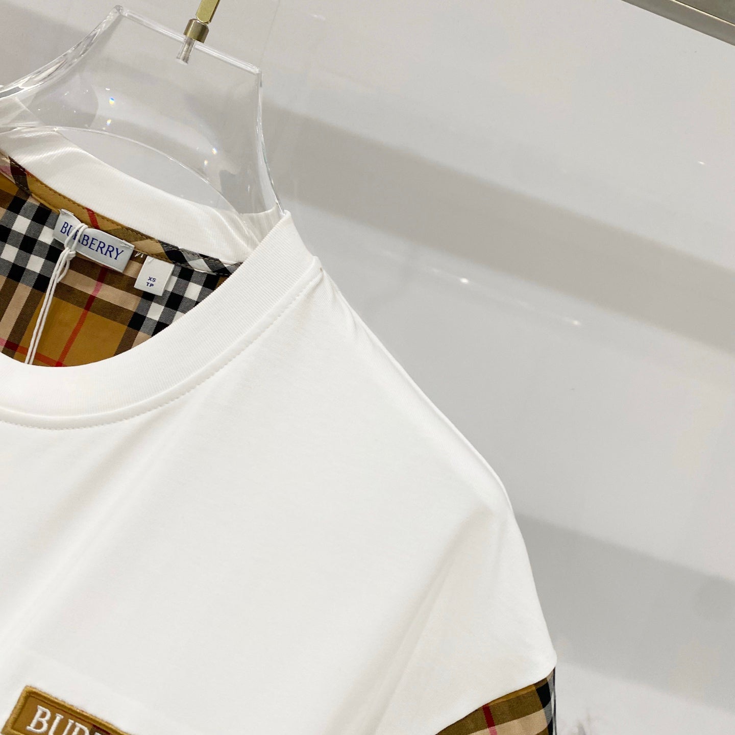 White T-shirt with plaid sleeve lining visible near the crew neckline