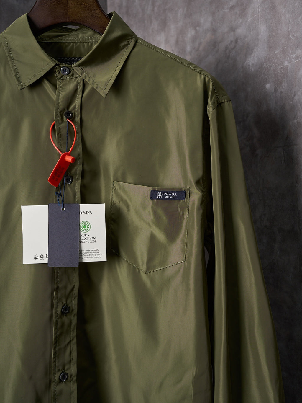 Olive Prada button-up shirt chest pocket close-up with hanging tags