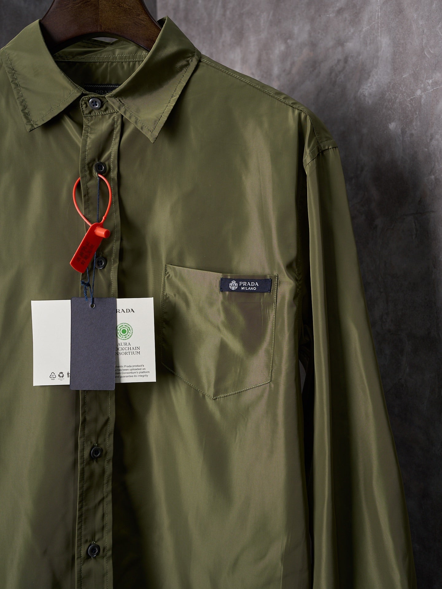 Olive Prada button-up shirt chest pocket close-up with hanging tags