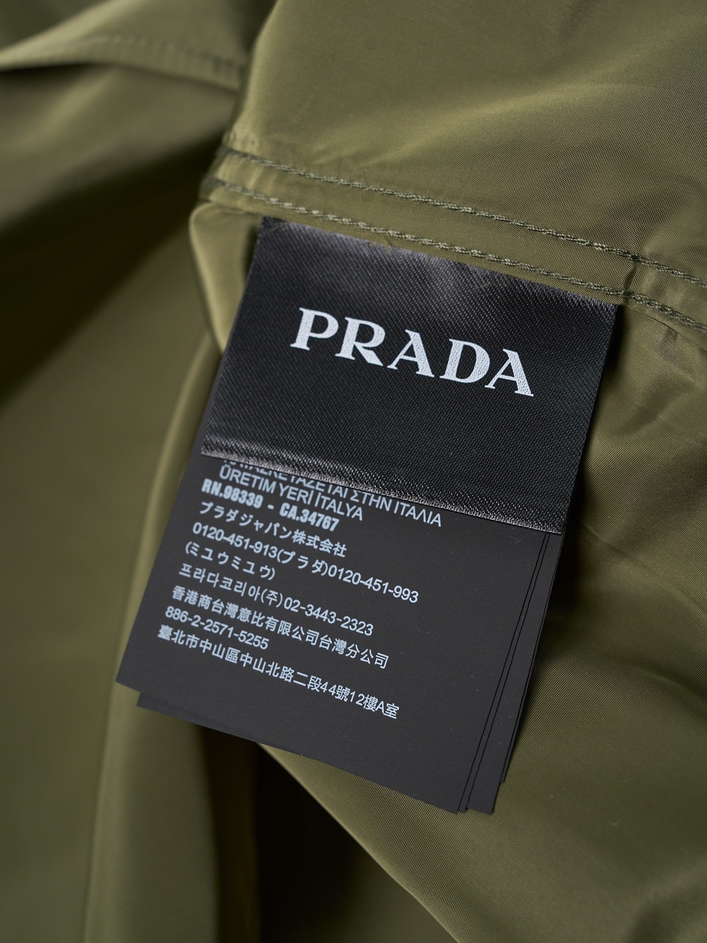 Prada garment care label on olive button-up shirt neck area