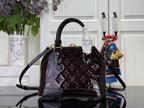 Louis Vuitton bag front view with dark monogram pattern, top handle with ruffle detail and shoulder strap.