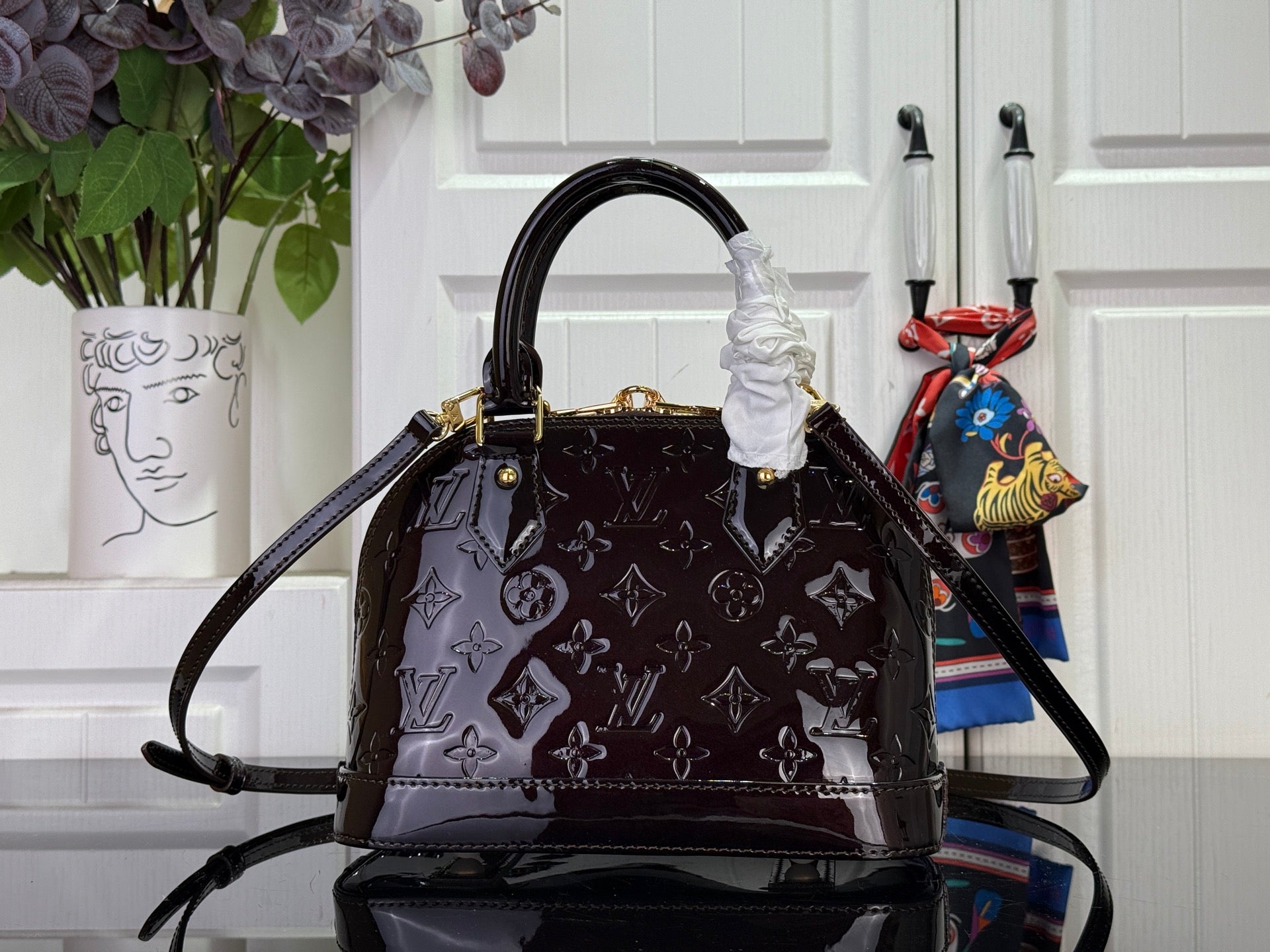 Louis Vuitton bag front view with dark monogram pattern, top handle with ruffle detail and shoulder strap.