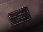 Louis Vuitton bag close-up of interior label on dark leather with gold stitching.