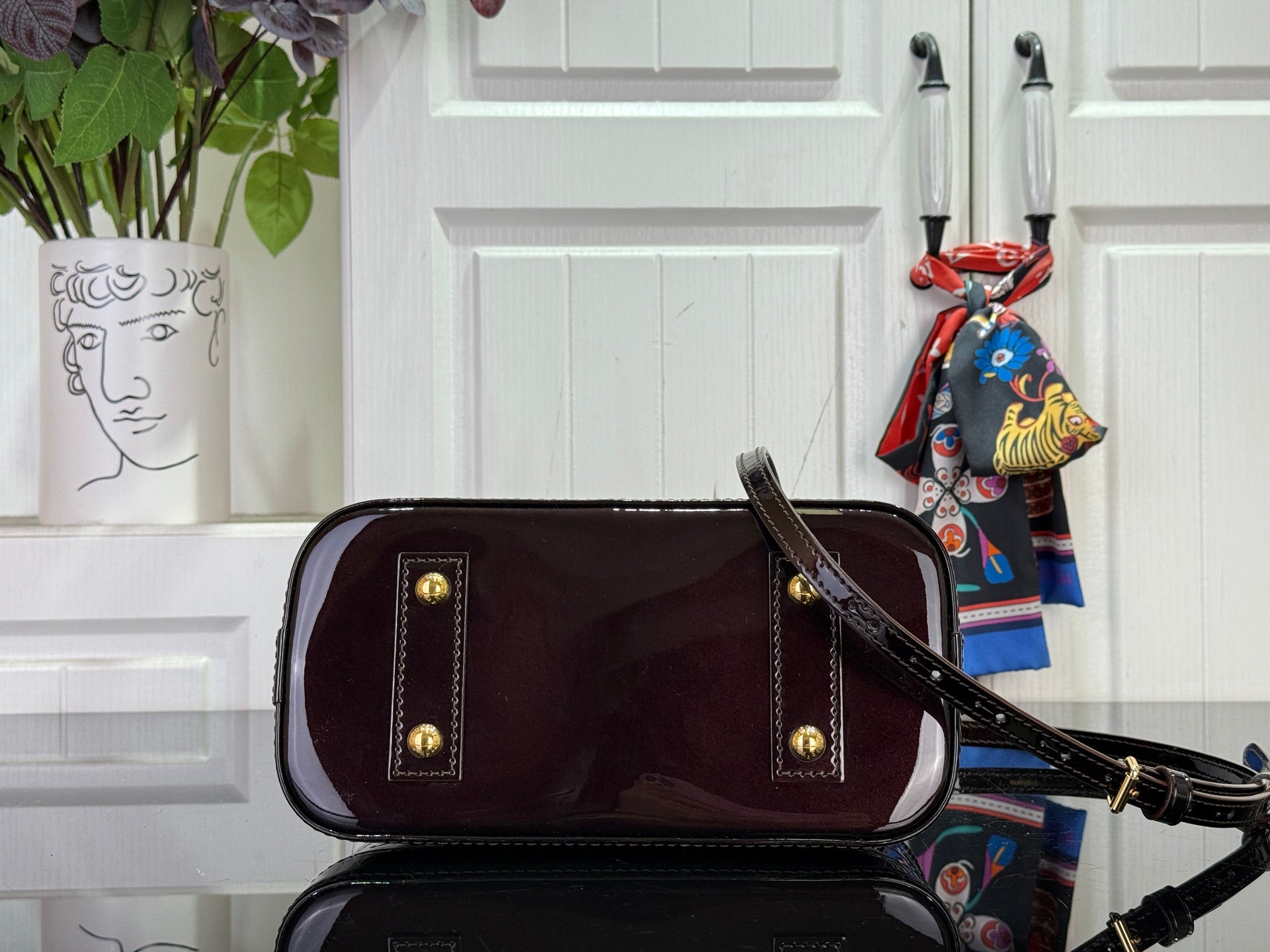 Louis Vuitton bag with burgundy leather-style body, gold hardware, top handle and shoulder strap.