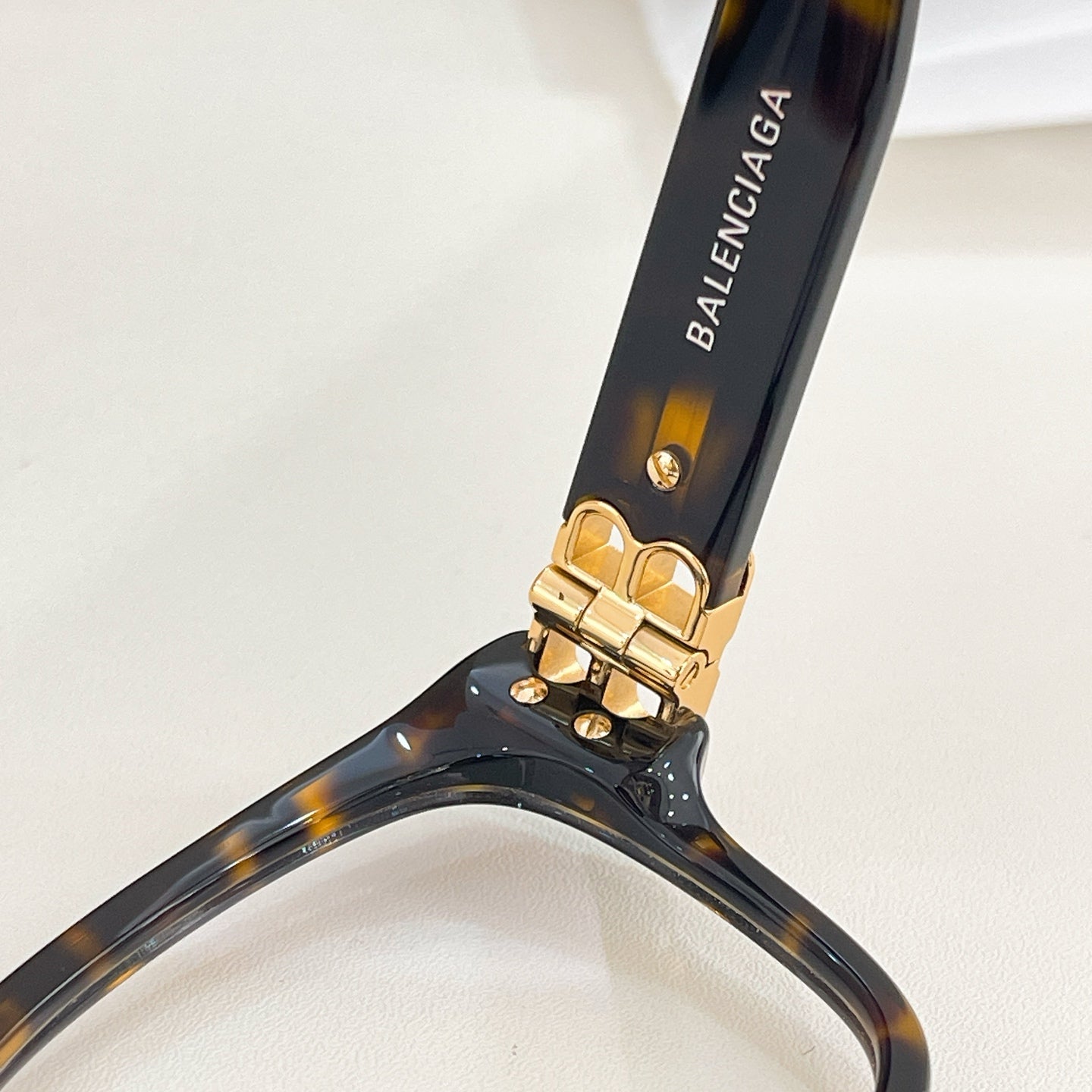 Balenciaga eyeglass temple with dark tortoiseshell finish and gold logo hinge