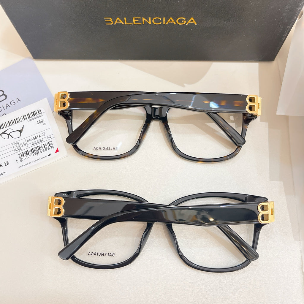 Two Balenciaga eyeglasses with clear lenses, dark frames and gold BB temple accents