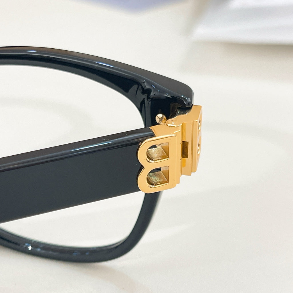 Balenciaga eyeglasses close-up: gold hinge hardware on dark navy frame