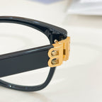 Balenciaga eyeglasses close-up: gold hinge hardware on dark navy frame