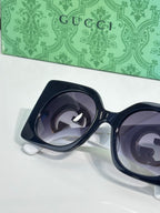 Gucci sunglasses close-up with dark blue thick frames and dark tinted lenses
