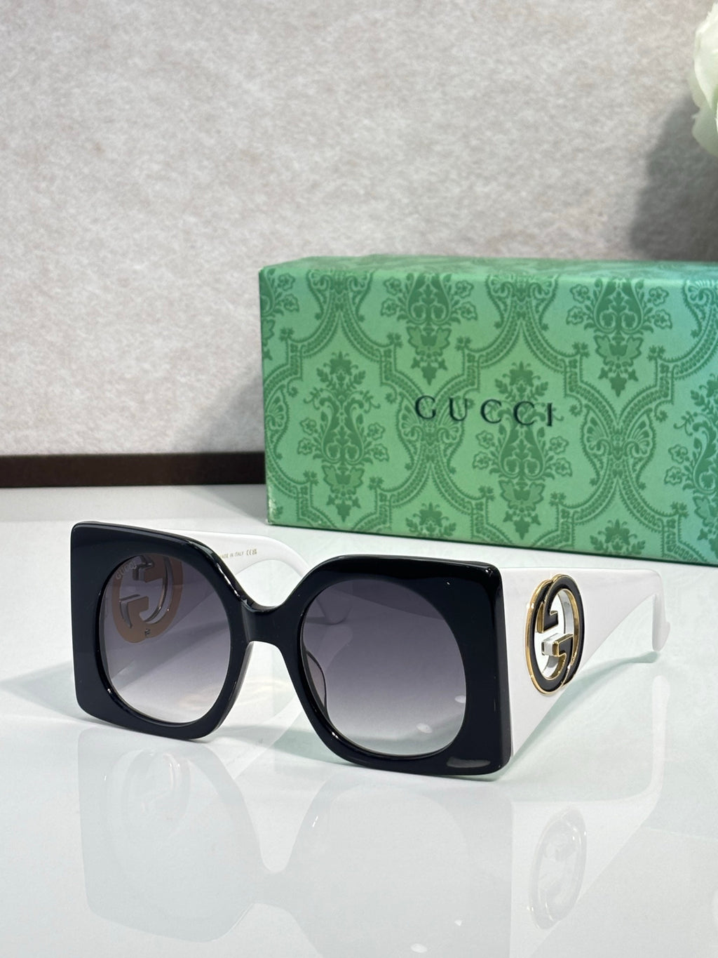 Gucci sunglasses with black square frames and dark tinted lenses, white temple tips