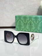 Gucci sunglasses with black square frames and dark tinted lenses, white temple tips