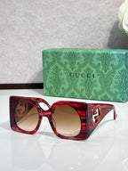Gucci sunglasses with red square frames and amber tinted lenses, gold logo detail