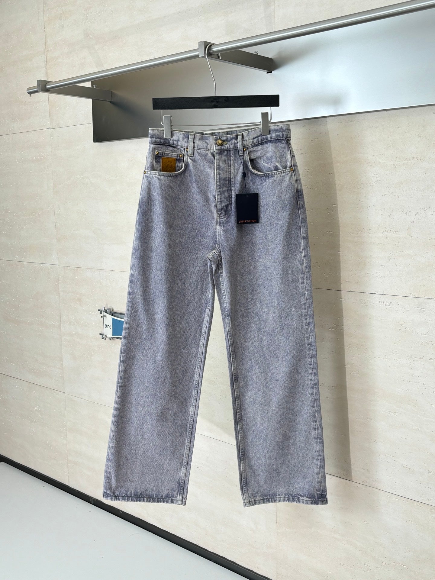 Light blue denim pants on hanger with front button and two front pockets