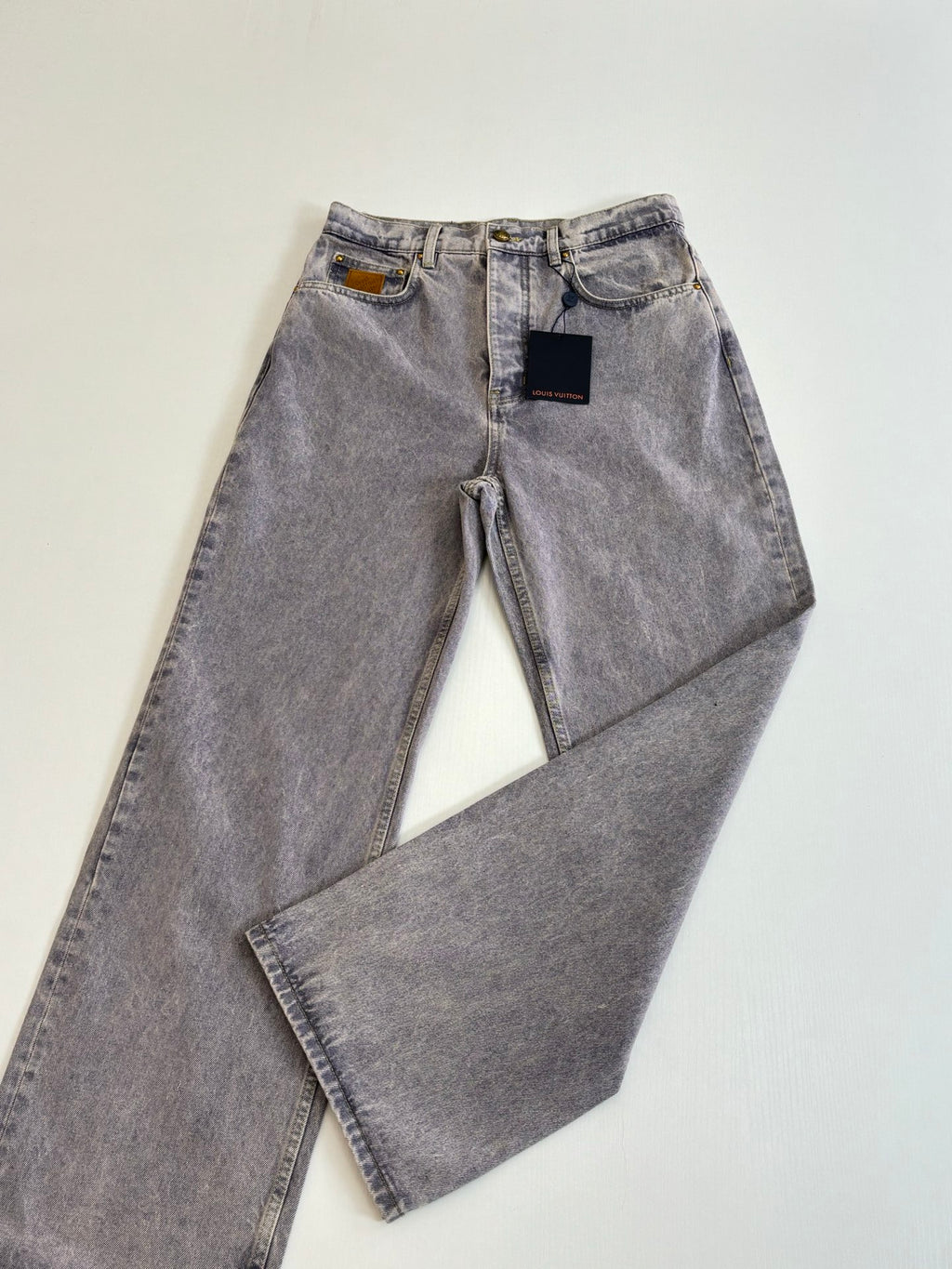 Pair of light blue denim pants laid flat, showing zipper fly and front pockets
