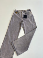 Pair of light blue denim pants laid flat, showing zipper fly and front pockets