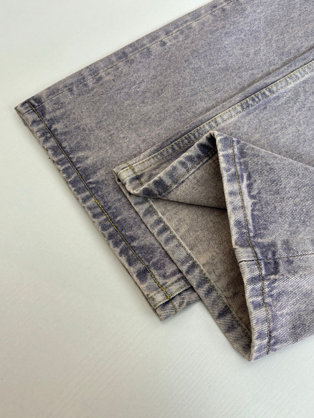 Folded light blue denim pants showing side seams and pocket panels