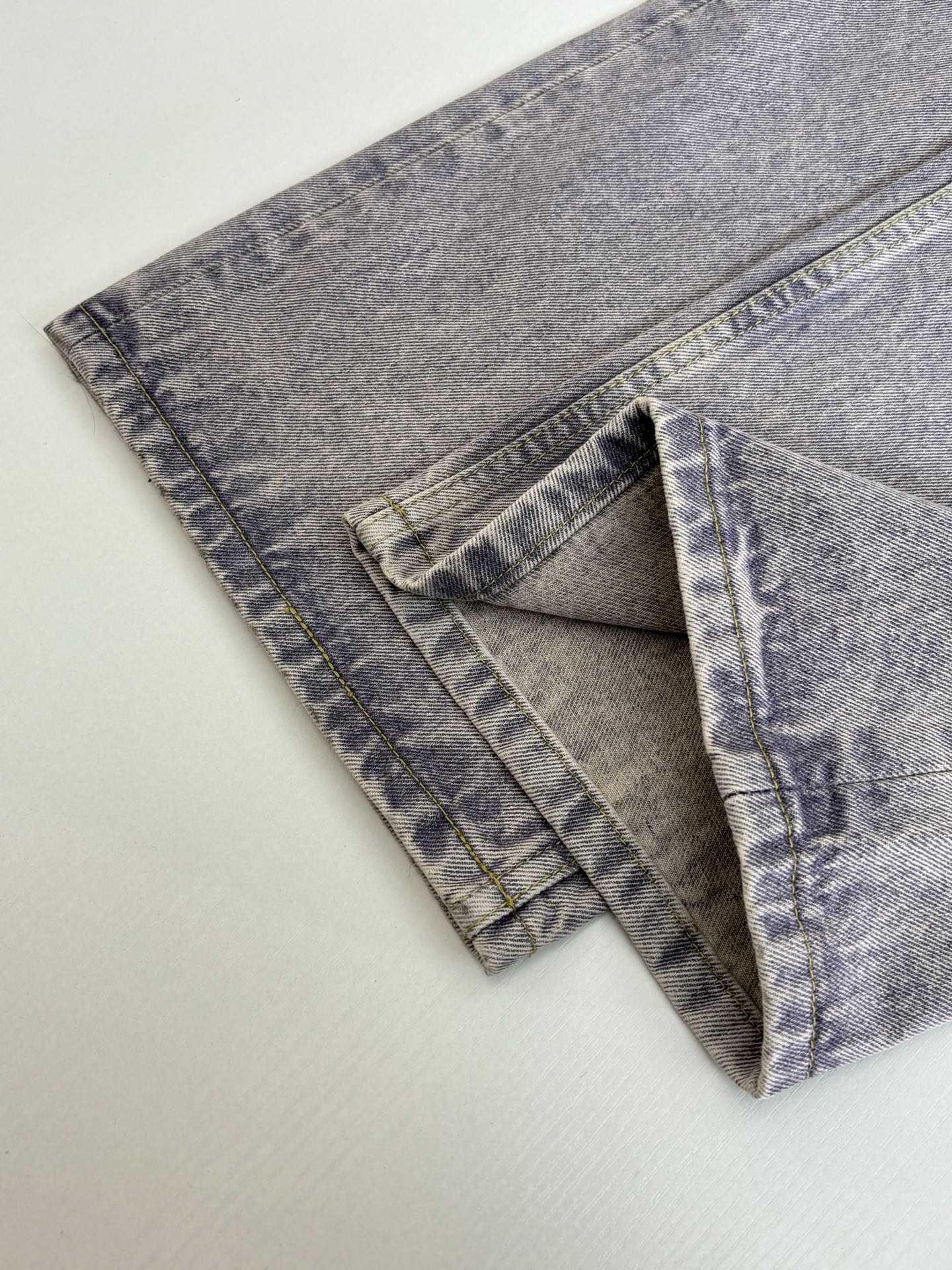 Folded light blue denim pants showing side seams and pocket panels