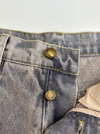 Close-up of light blue denim pants back pockets with gold-toned button accents