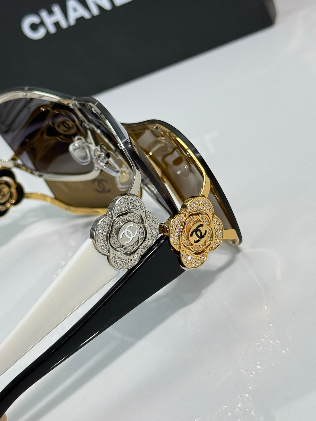 Sunglasses close-up: round silver and gold emblems on bridge, dark and amber lenses