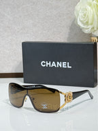 Sunglasses with amber lenses, gold-tone frame, ornate emblem on bridge