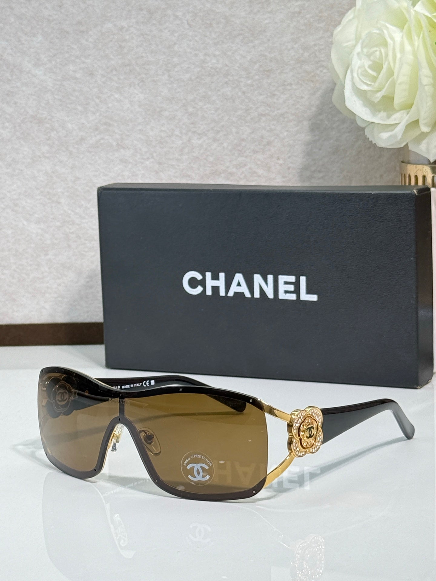 Sunglasses with amber lenses, gold-tone frame, ornate emblem on bridge