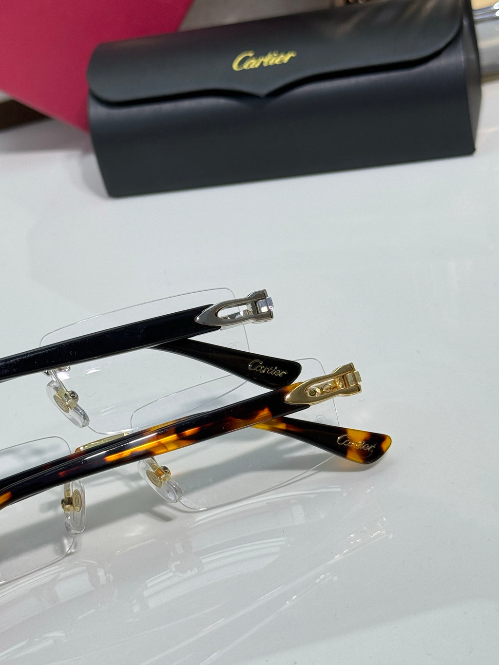 Gold hinge detail on clear eyeglasses with black temple tips