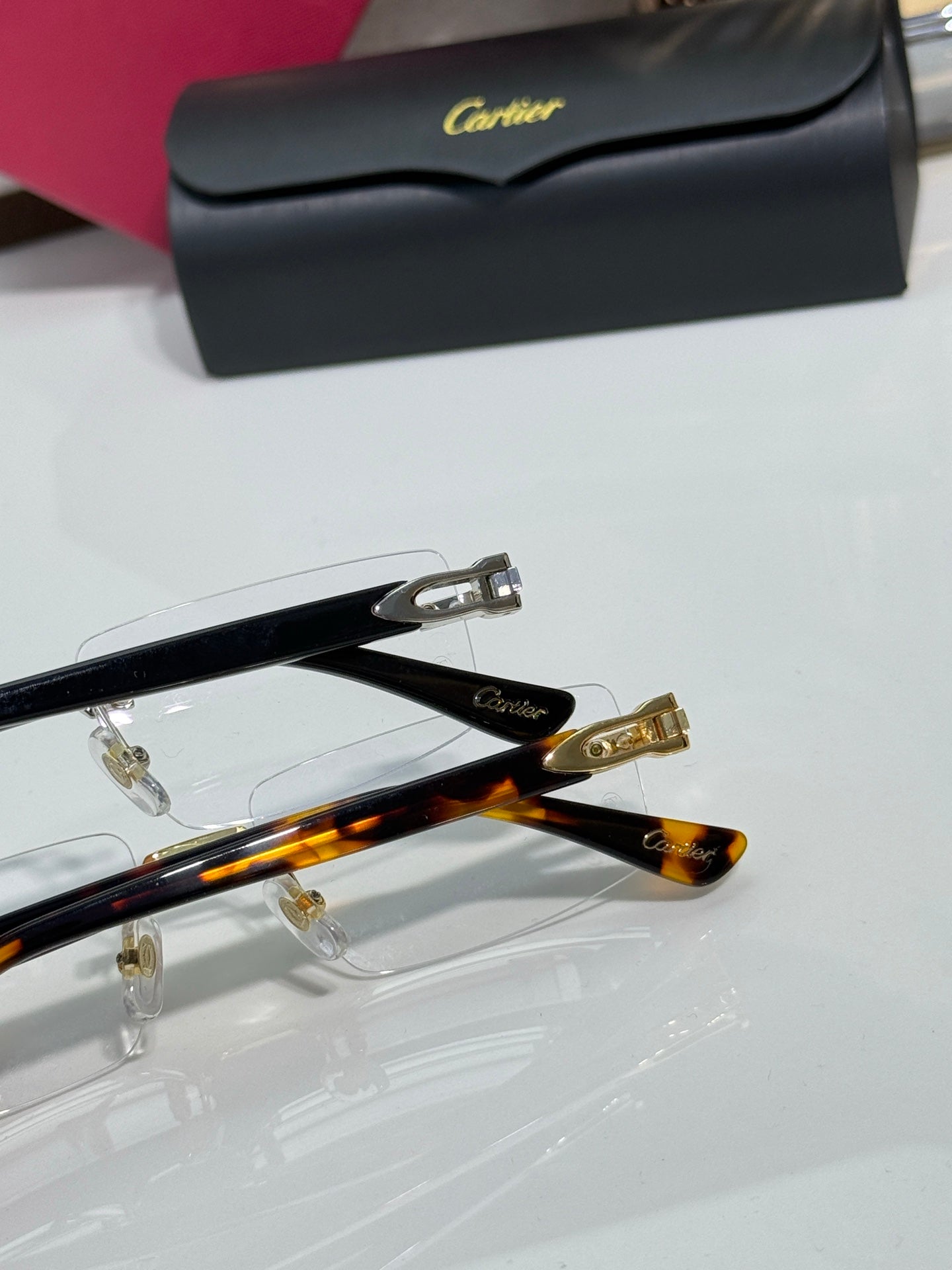 Gold hinge detail on clear eyeglasses with black temple tips