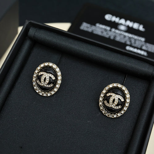 Round stud earrings with black enamel CC logo and crystal halo, gold-tone backs